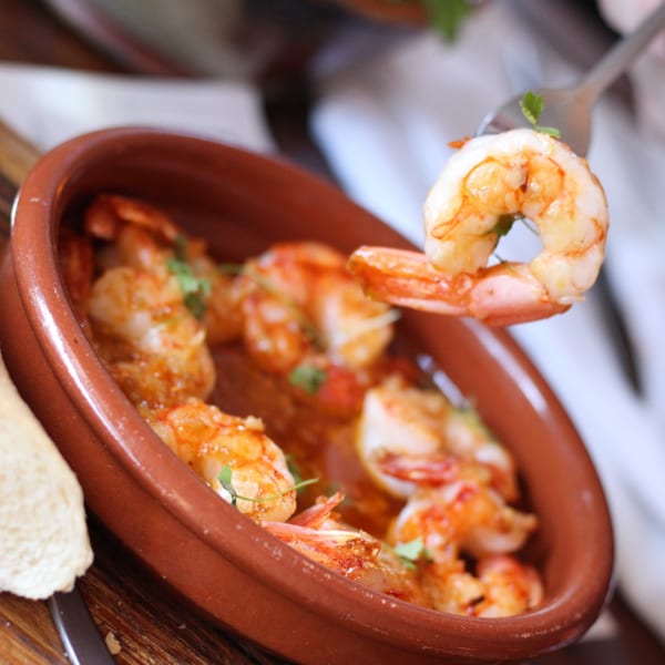 A fork lifts a succulent shrimp from a terracotta bowl of Pinch Kitchen+Bar's American-style shrimp scampi.