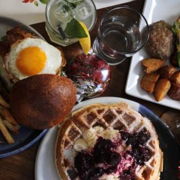A table spread with Pinch Kitchen+Bar's American breakfast items, including waffles, eggs, and drinks.